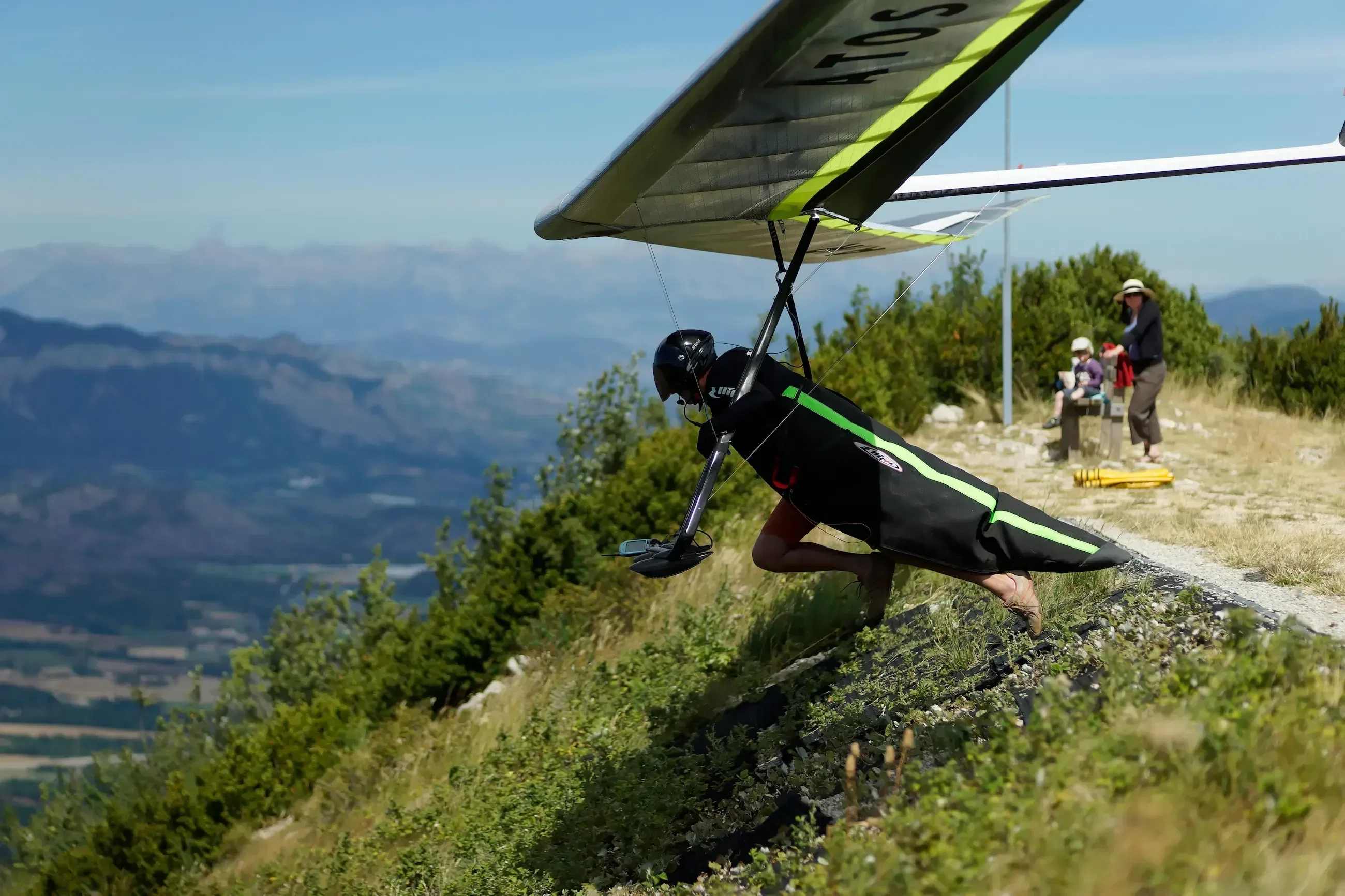 A man running down a cliff with a para glider to fly