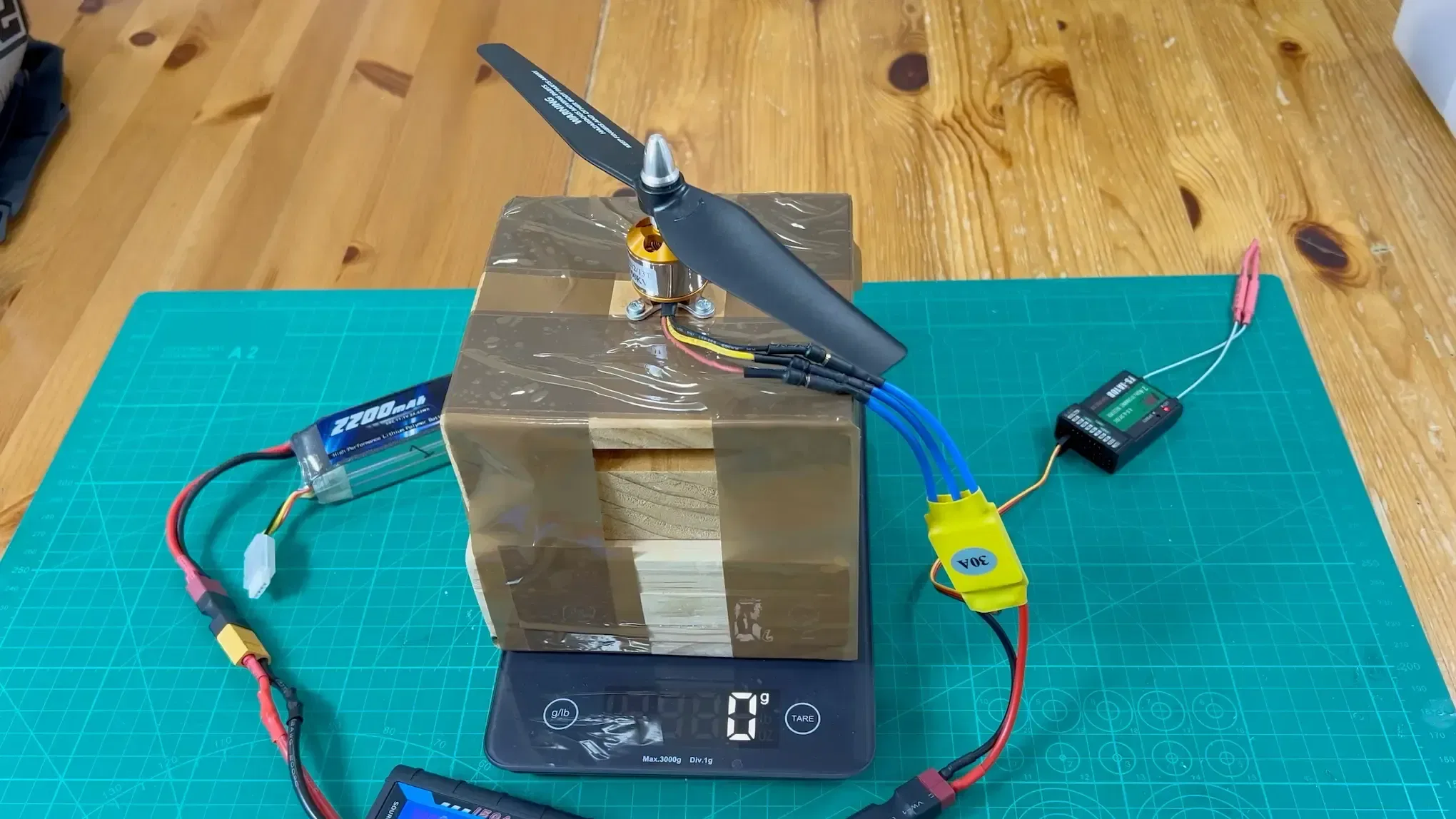 hero-image-brushless-motor-with-9x4-prop-mounted-on-a-piece-of-wood-setting-on-a-kitchen-scale